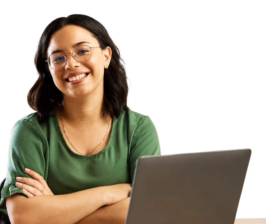 Mujer sonriente con gafas, brazos cruzados frente a una laptop